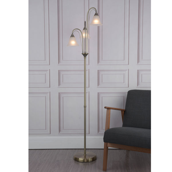 A bronze floor lamp with three frosted glass shades, next to a dark gray armchair.