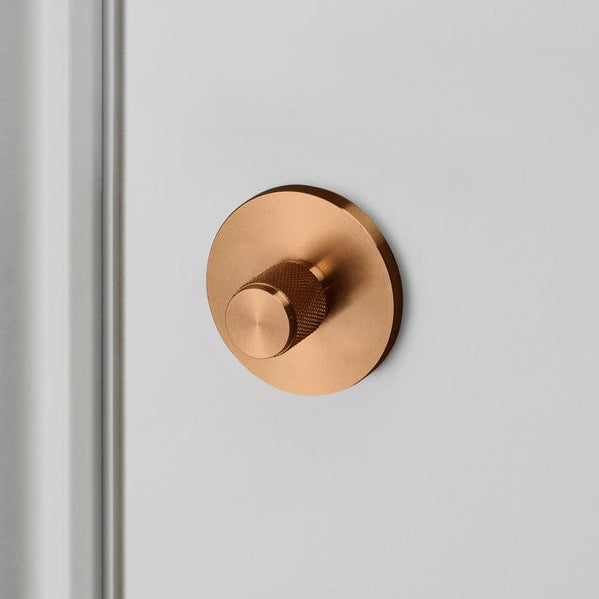 Round copper dimmer switch on a white wall