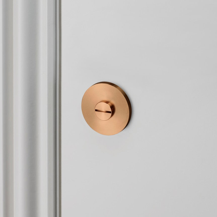Round copper door lock on a white door