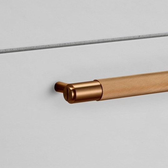 Close up of a knurled brass handle on a white wall