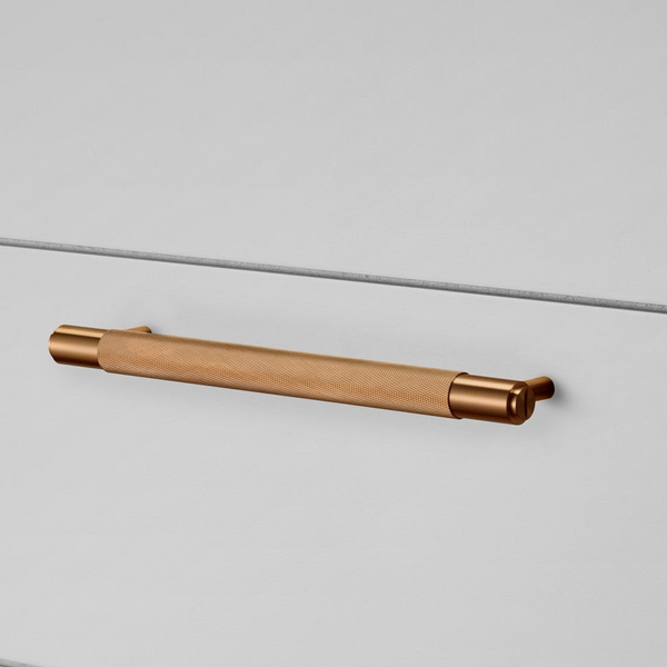 Knurled solid brass pull bar handle on a white drawer