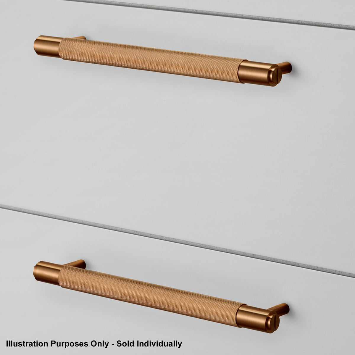 Two knurled brass handles on a light grey drawer front