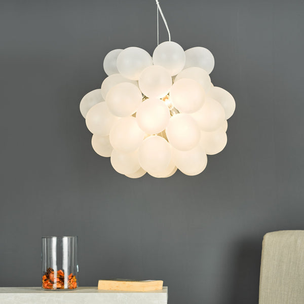 White bubble chandelier hanging from the ceiling, illuminating a dark gray wall and a table with a vase
