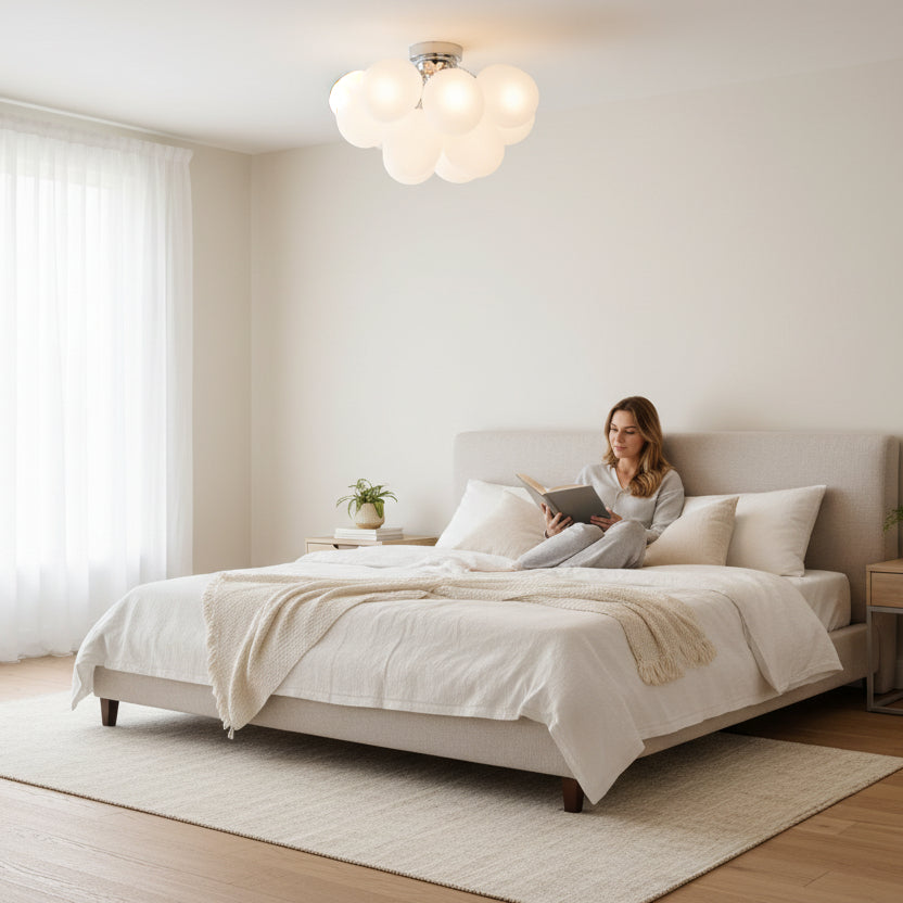 Woman reading a book in bed under a cloud-shaped ceiling light