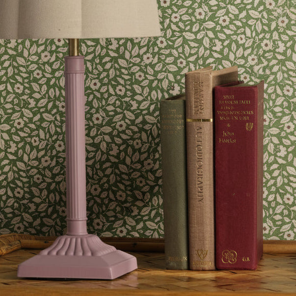 Joules Buscot table lamp in matt pink with natural linen shade next to three books on a wooden surface
