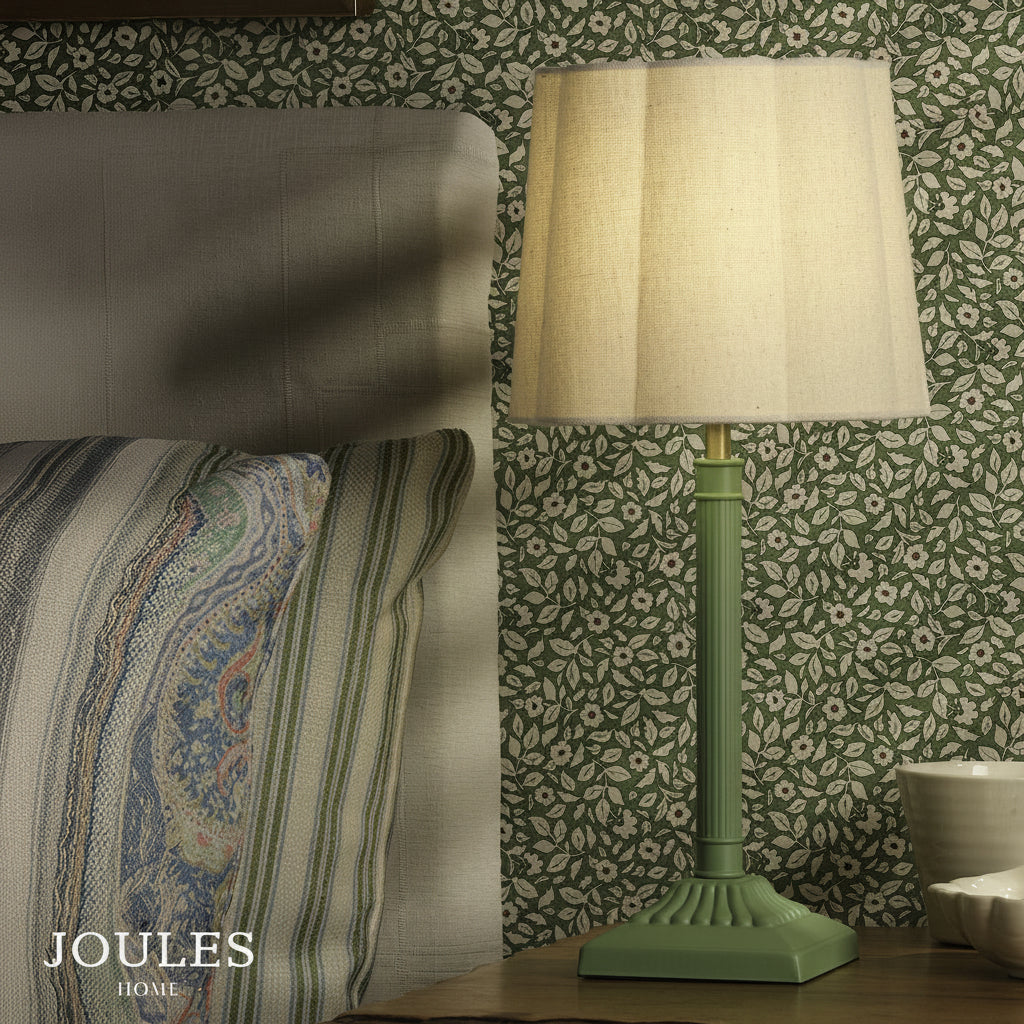 Joules Buscot table lamp in matt green with a natural linen shade on a bedside table
