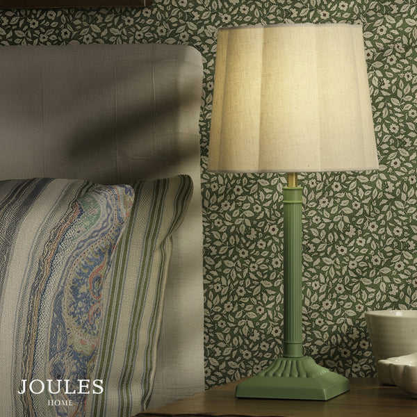 Joules Buscot table lamp in matt green with a natural linen shade on a bedside table
