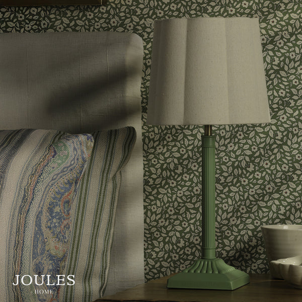 Joules Home green table lamp with a pleated fabric shade on a wooden bedside table