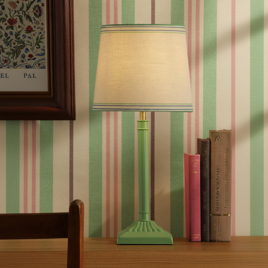 Joules Buscot table lamp in matt green with a tapered linen shade on a wooden surface