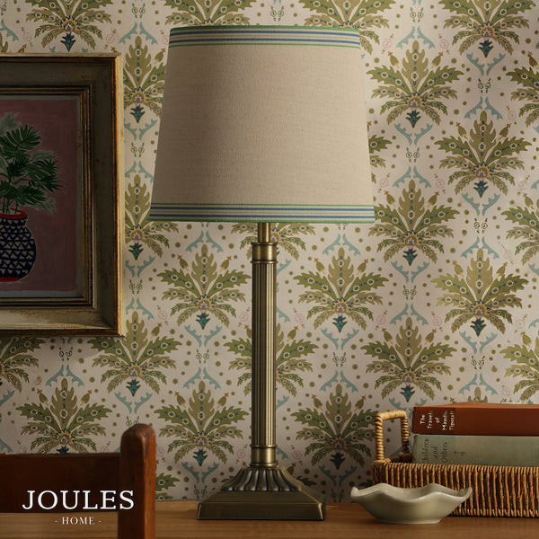 Joules Home brass table lamp with a striped fabric shade against patterned wallpaper