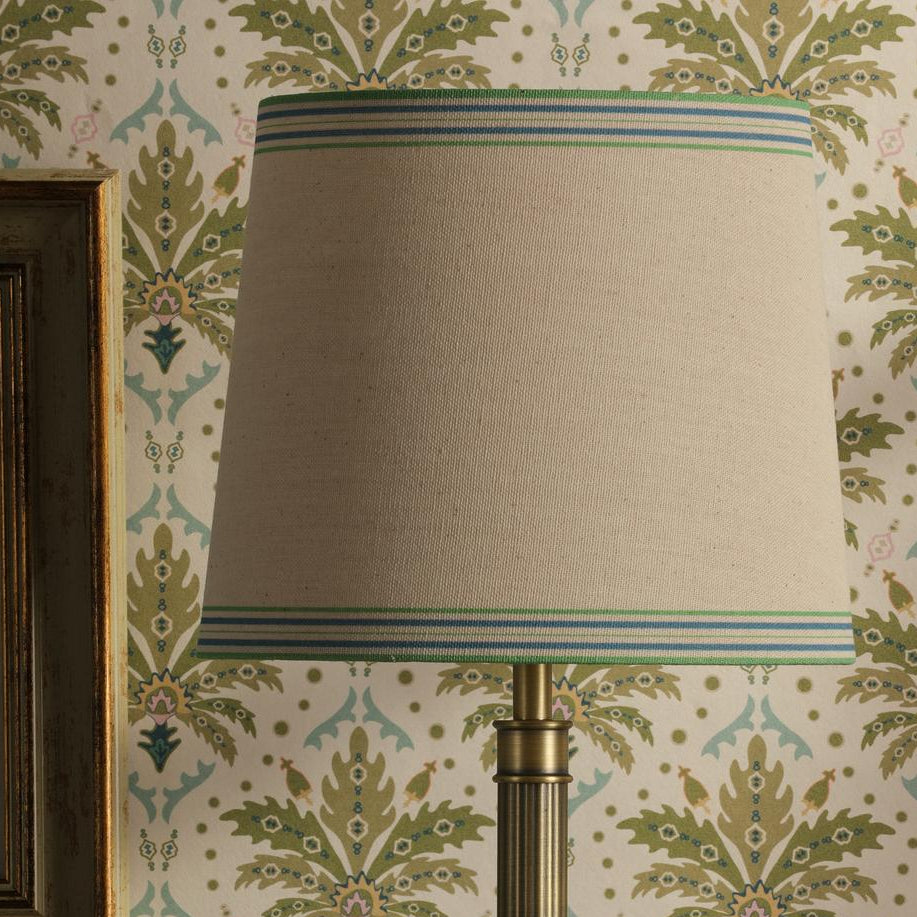 Joules Buscot table lamp featuring an antique brass base and a tapered linen shade with blue and green striped trim