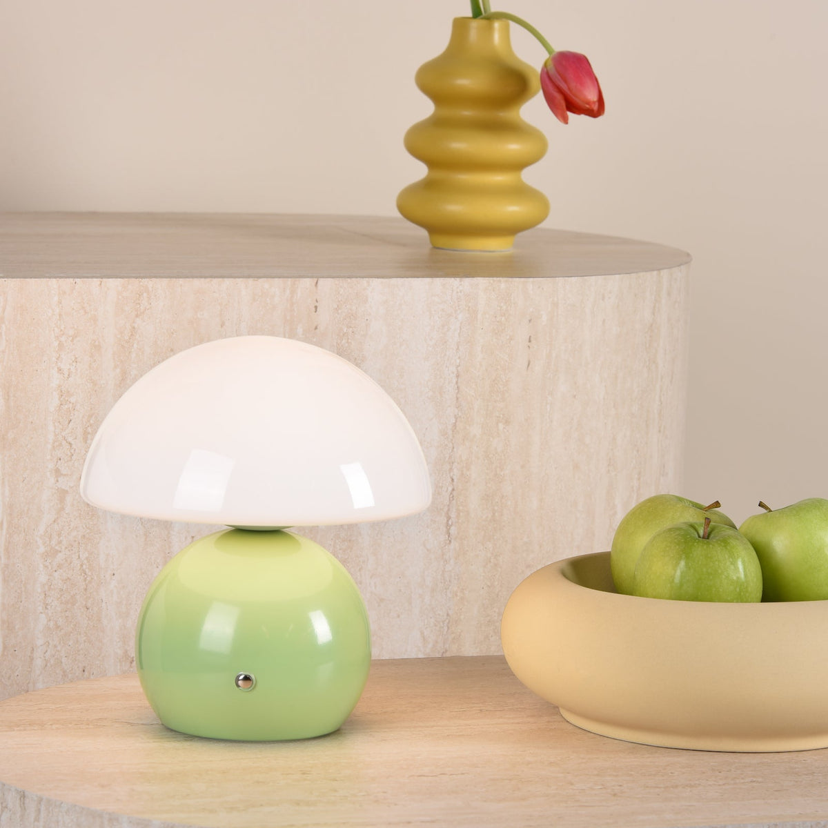 Mushroom table lamp with a green base and white shade, next to a bowl of green apples