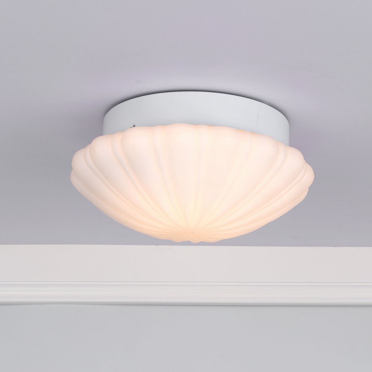 White ceiling light fixture with a fluted, shell-shaped glass shade