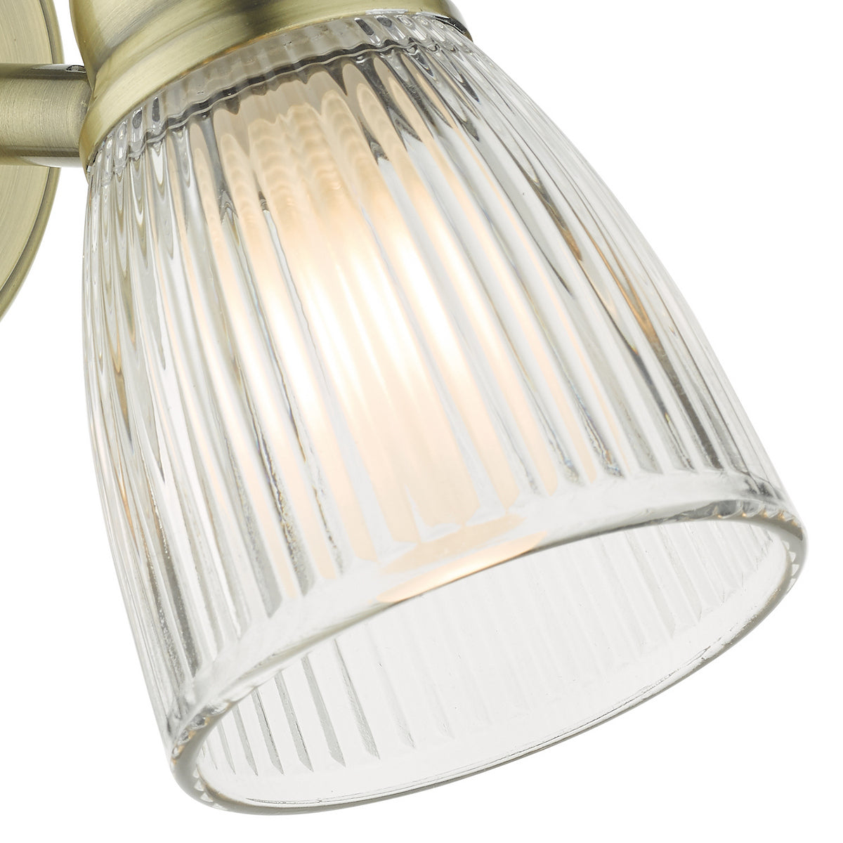 Close-up of a ribbed glass light shade with a warm glow from the bulb.
