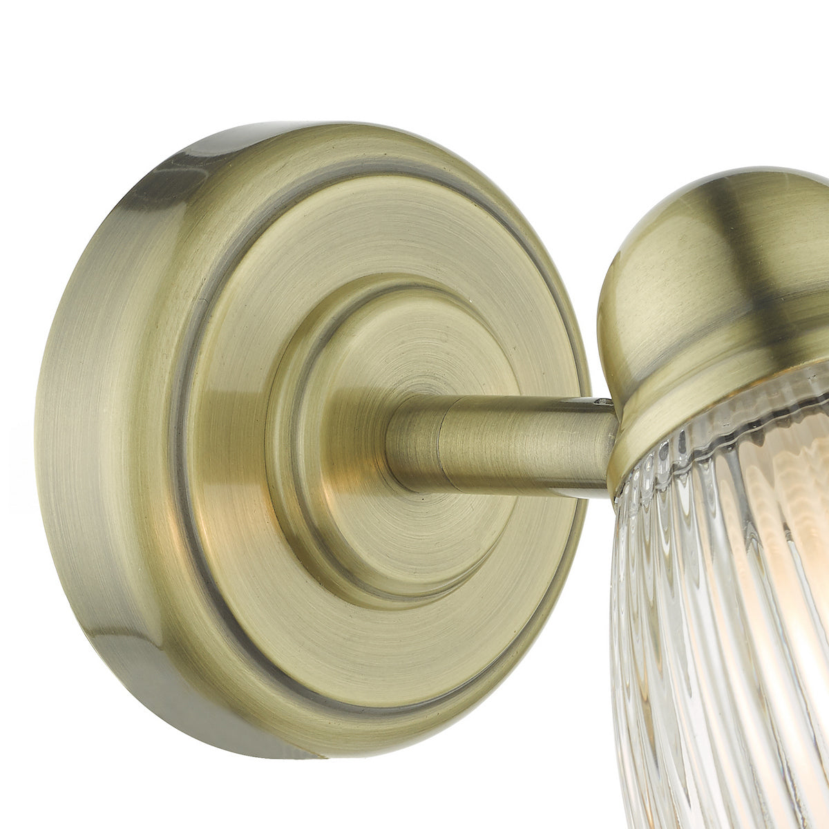 Close-up of a brass wall light with a ribbed glass shade, showing the intricate details of its design.