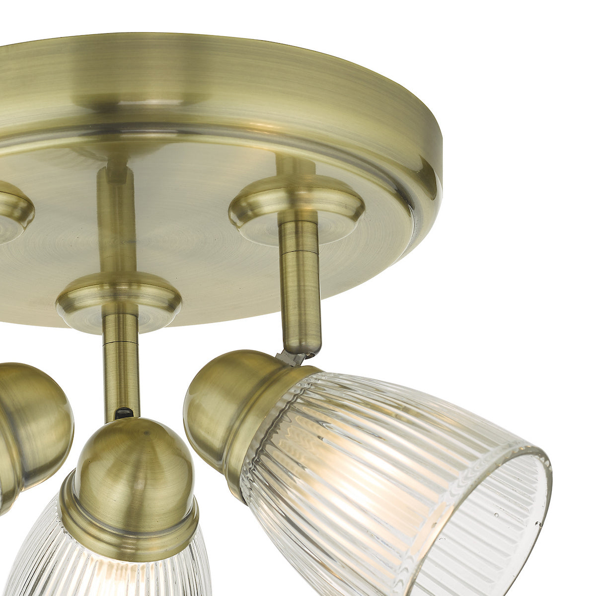 Close-up of a brass ceiling light with three ribbed glass shades, angled downwards.