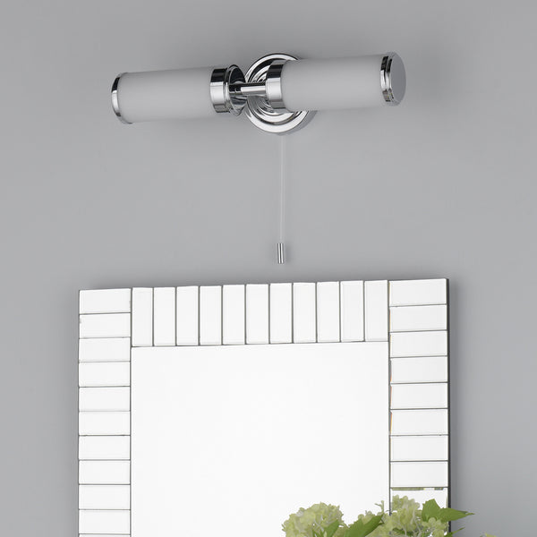 Chrome bathroom light with two frosted glass shades and a pull cord switch above a mirror.