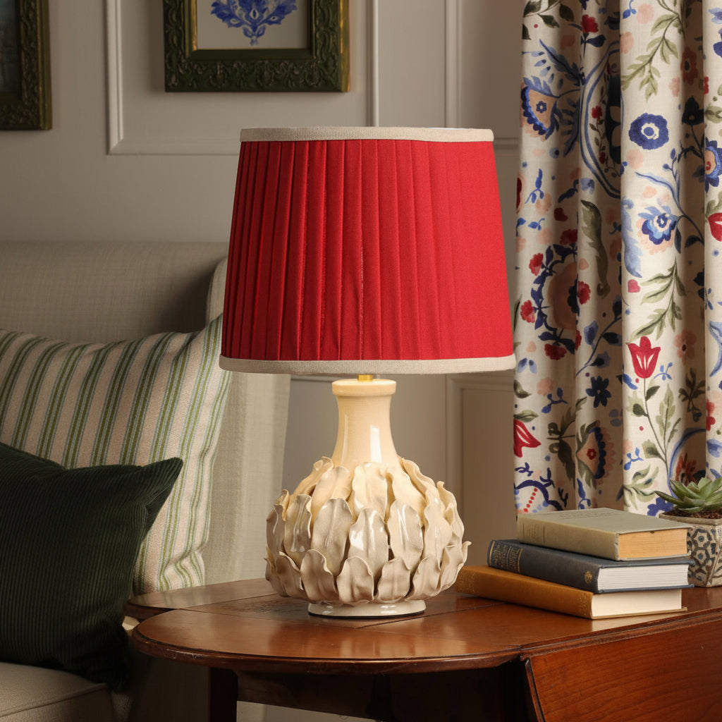 Table lamp with cream ceramic leaf base and pleated red fabric shade