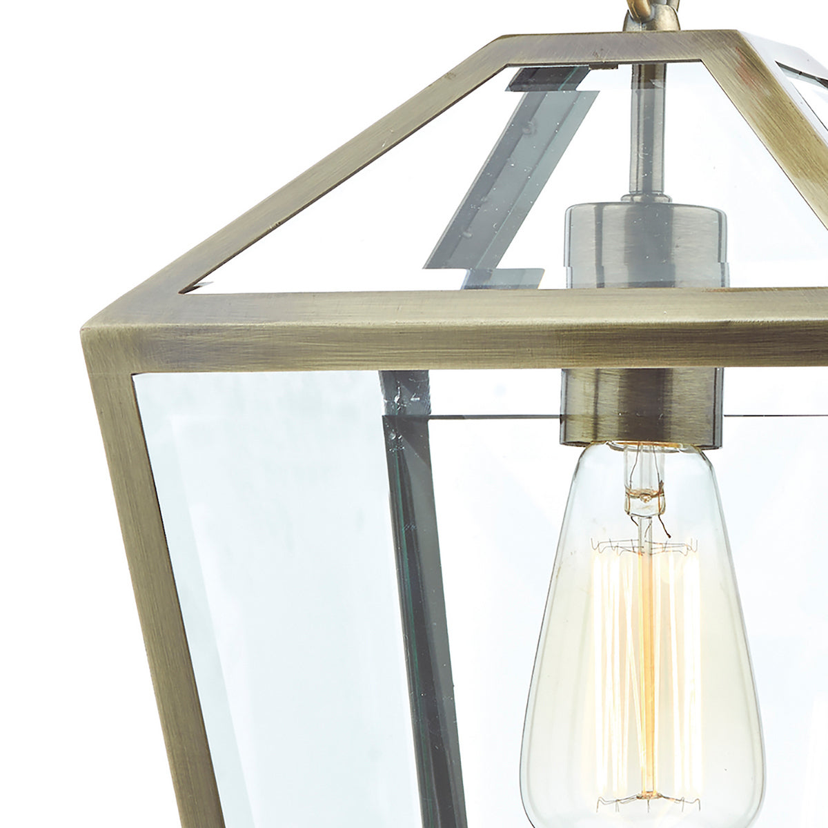 Close-up of a brass lantern pendant light with clear glass panels and an exposed filament bulb.