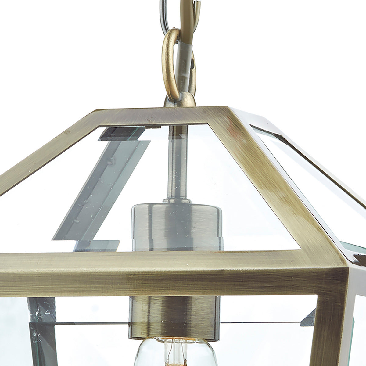 Close-up of a brass lantern pendant light with clear glass panels and an exposed bulb.