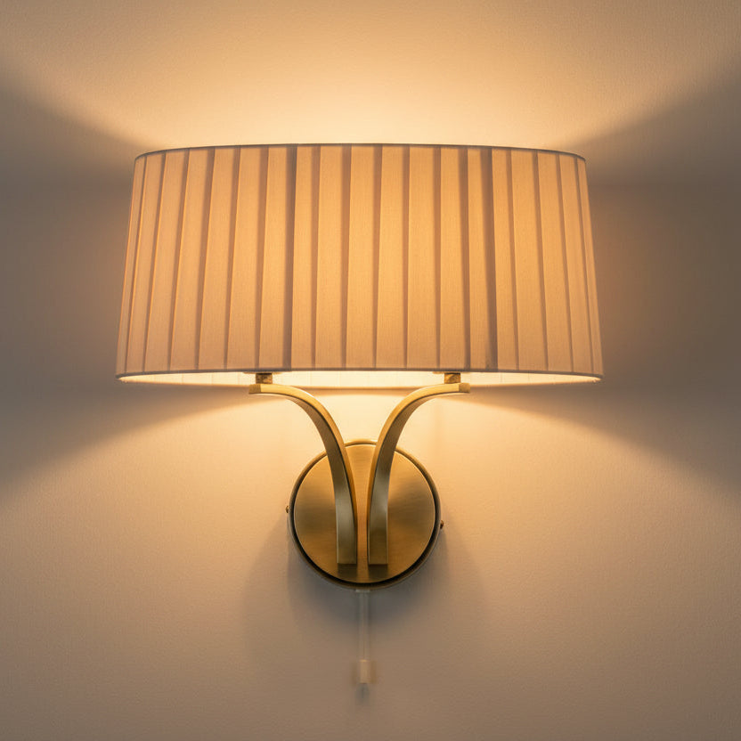 Wall mounted light fixture with a pleated fabric shade and a brass base