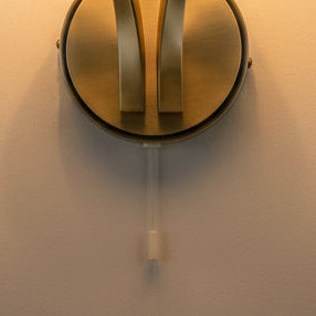 Close up of a brass wall sconce with a pull chain switch