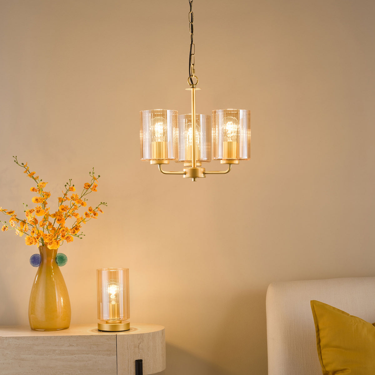 Three-light chandelier with ribbed glass shades and a matching table lamp on a console table