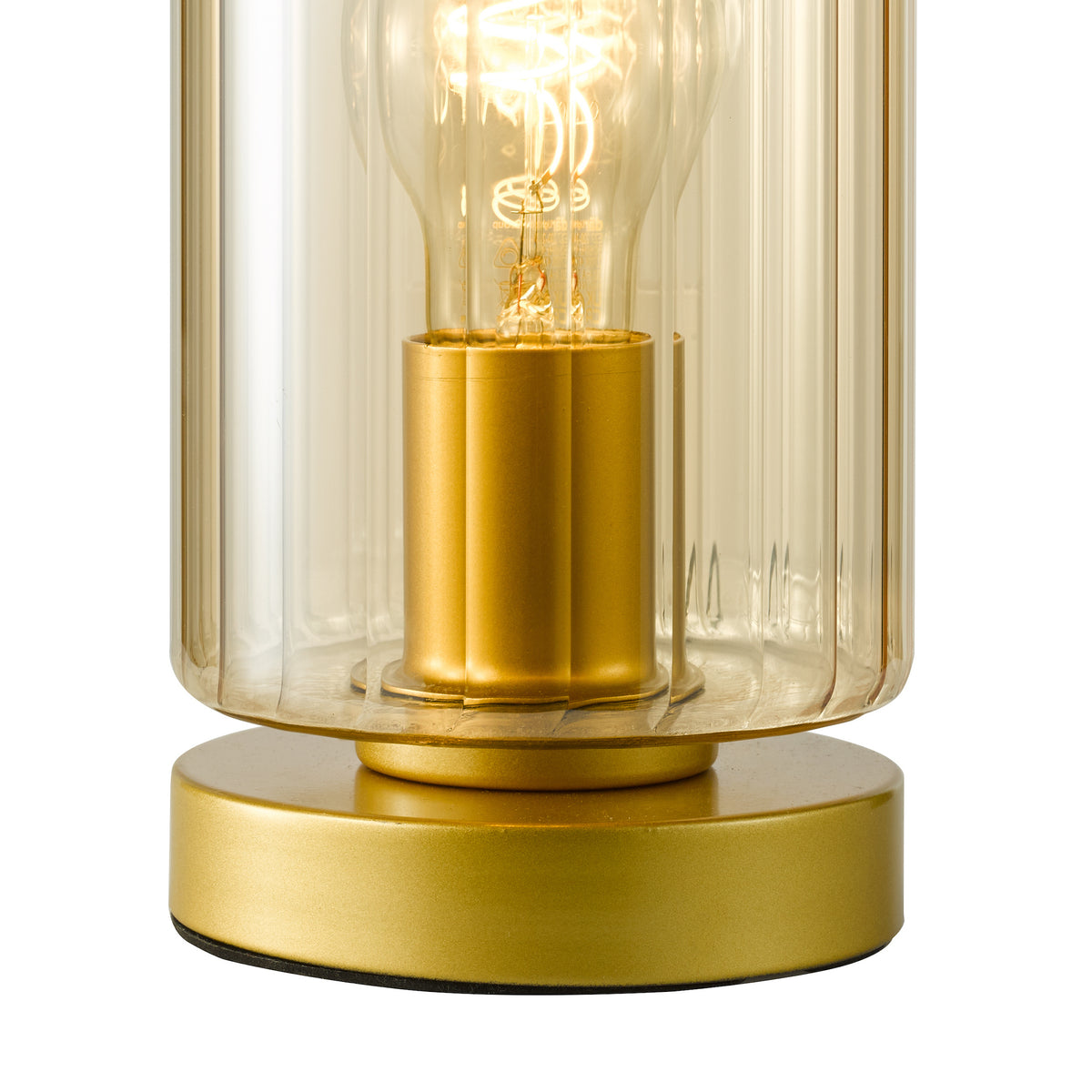 Close up of a gold table lamp with a clear ribbed glass shade and an exposed filament bulb
