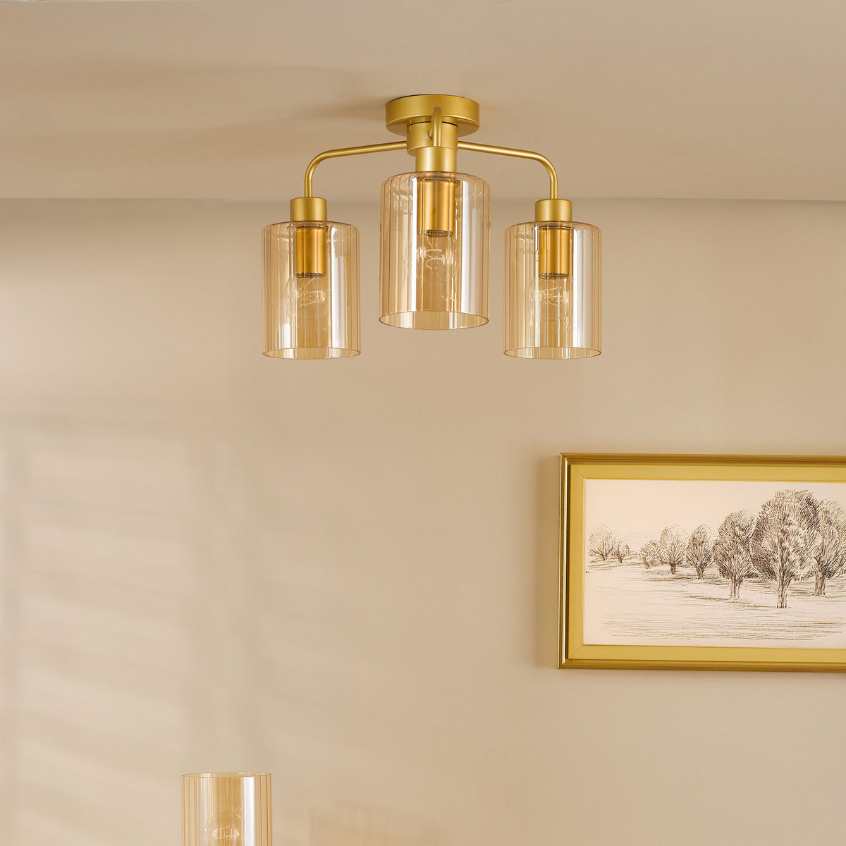 Three light gold ceiling fixture with amber ribbed glass shades