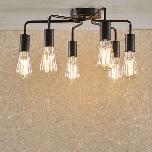 Black ceiling light with six exposed Edison bulbs illuminating a textured beige wall.