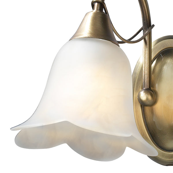 Close-up of a brass wall sconce with a frosted, bell-shaped glass shade.