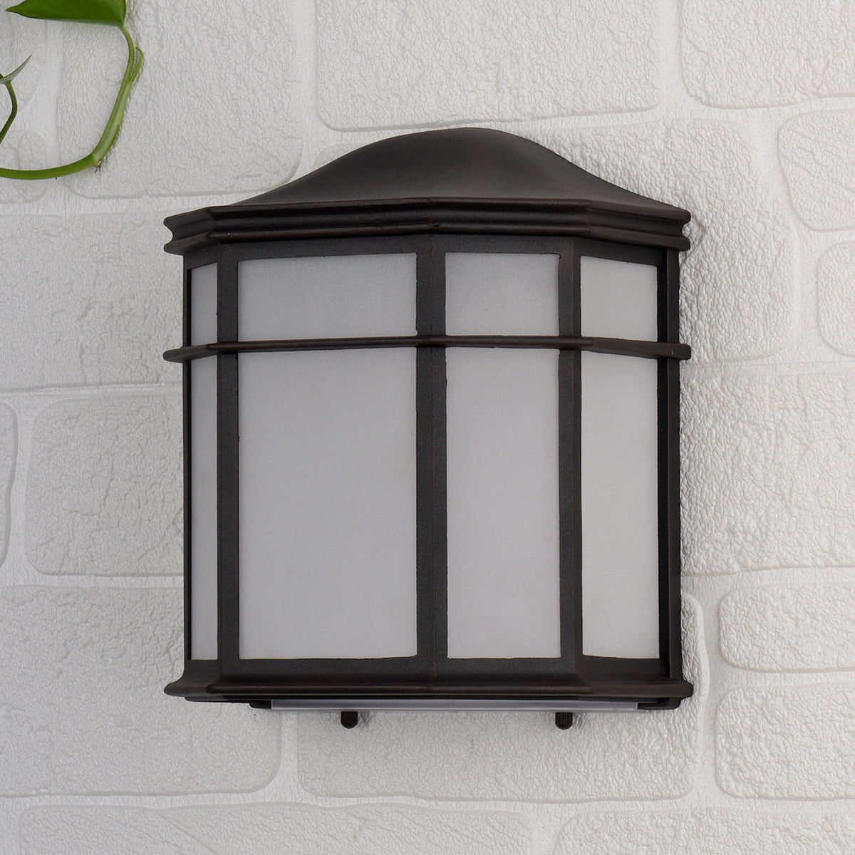 Dark brown outdoor wall light with frosted glass panels on a white brick wall.