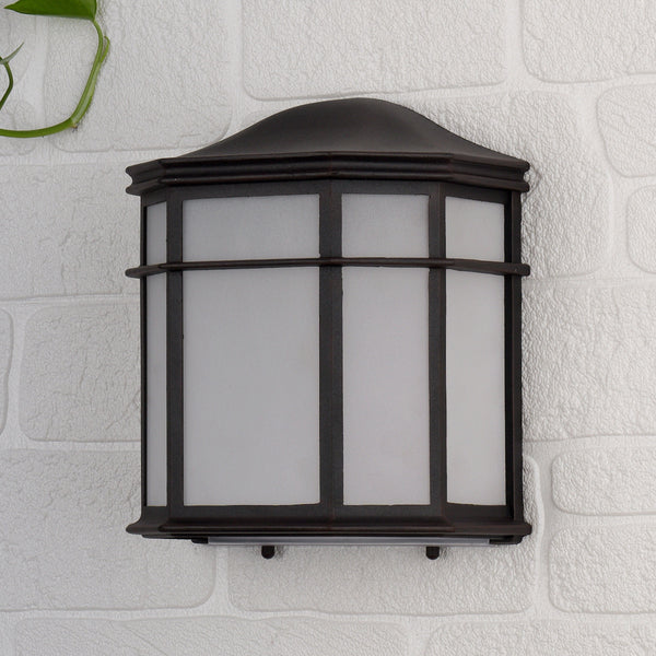 Dark brown outdoor wall light with frosted glass panels on a white brick wall.