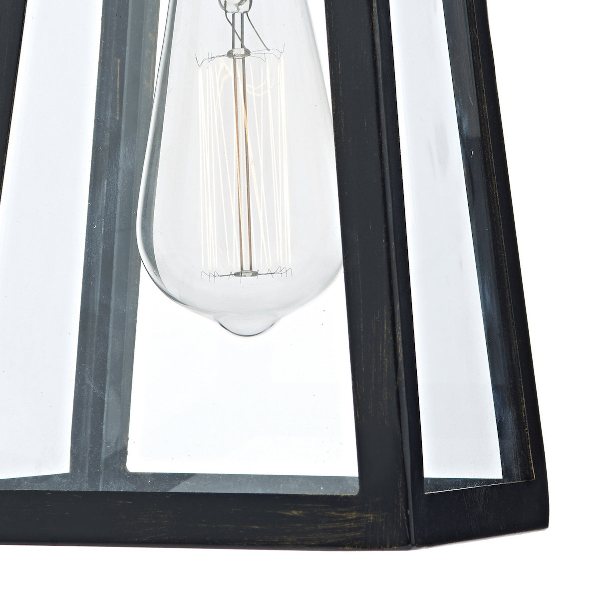 Close-up of a clear light bulb with visible filaments inside a dark metal and glass lantern.