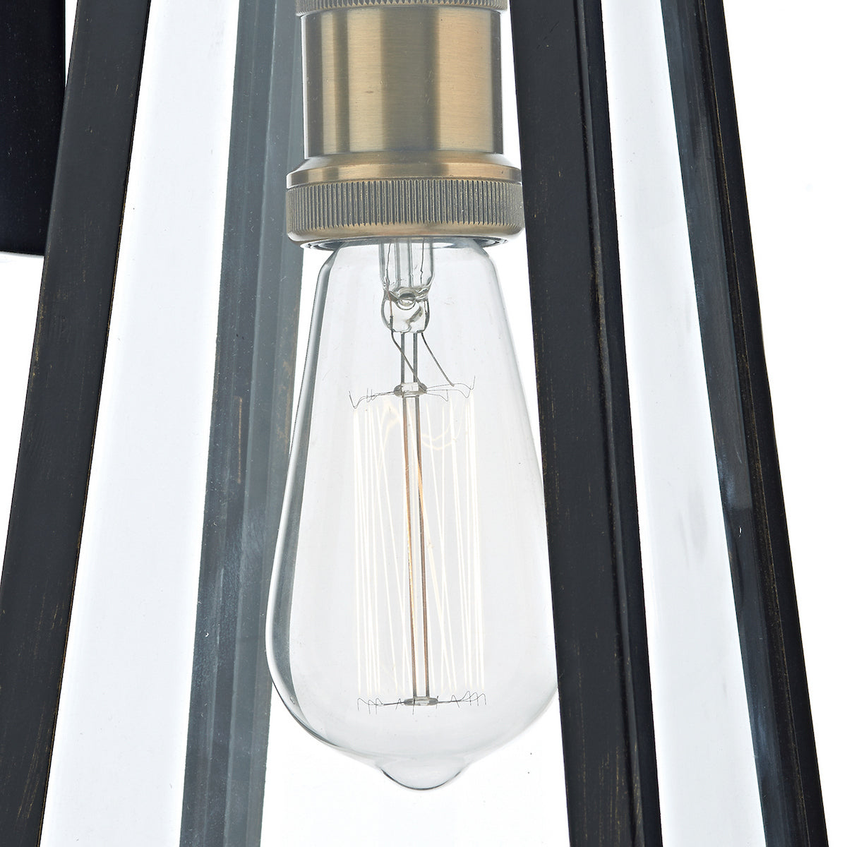 Close-up of a clear Edison bulb with visible filaments, set in a brass fixture within a dark metal frame.