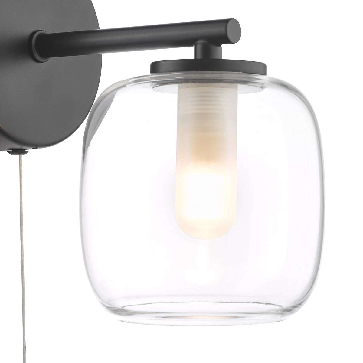 Black wall sconce with a clear glass shade and an illuminated bulb