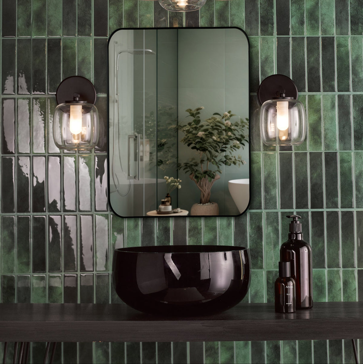 Bathroom with green subway tiles, black mirror, black basin, and two wall-mounted lights