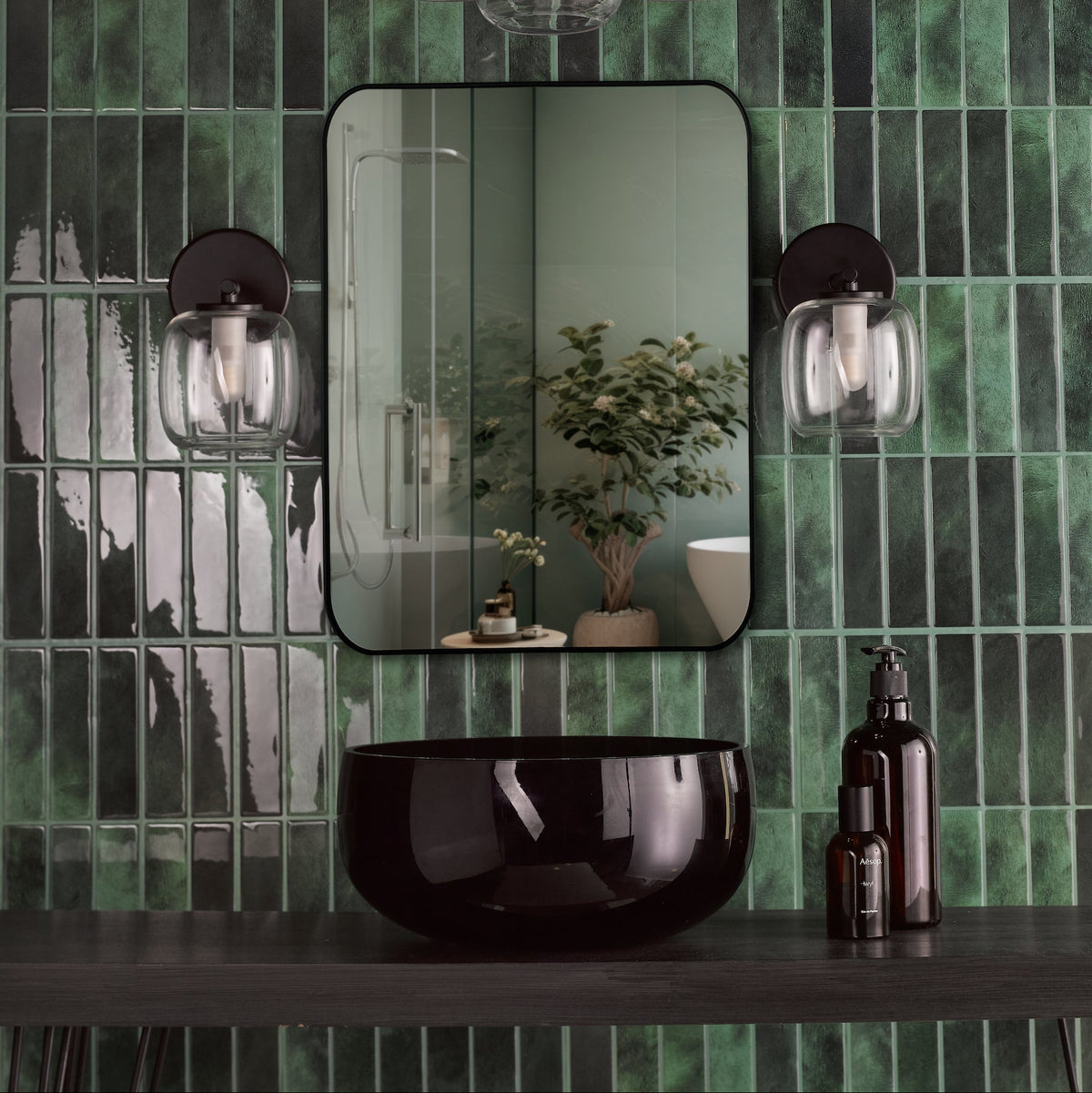 Bathroom with green subway tiles, black vanity, black basin, and two wall sconces