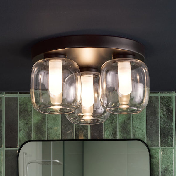 Three light ceiling fixture with clear glass shades and a dark bronze base
