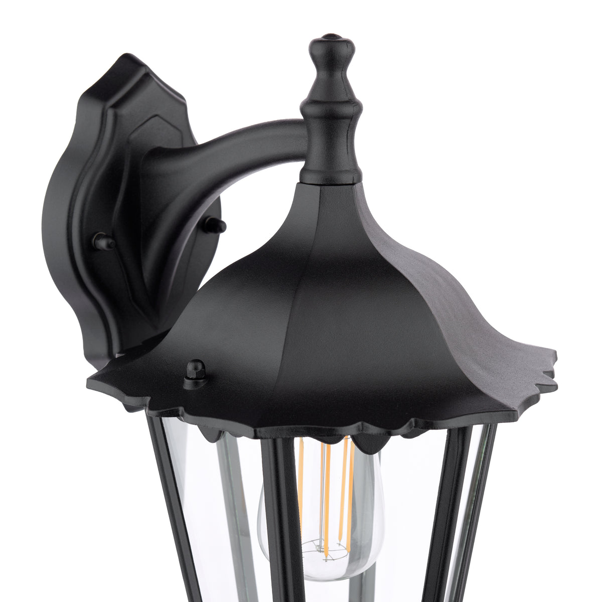 Black outdoor wall light with a decorative top finial and clear glass panels, showcasing an exposed filament bulb