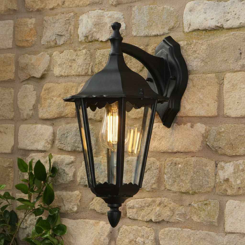 Black outdoor wall lantern with clear glass panels and an exposed filament bulb