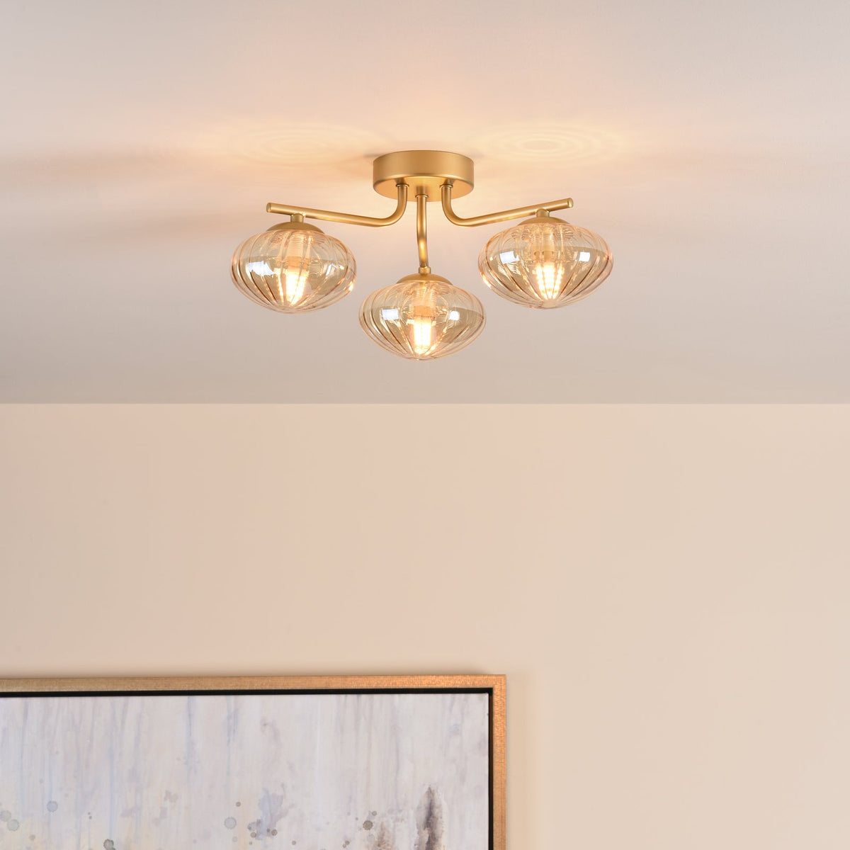 Three-light ceiling fixture with ribbed glass shades and a gold finish