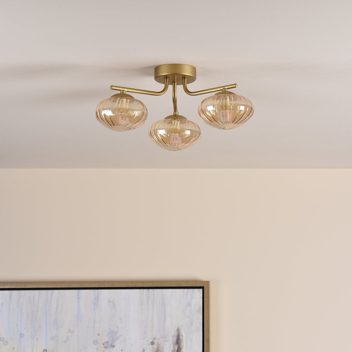 Three-light ceiling fixture with amber ribbed glass shades and a brass finish