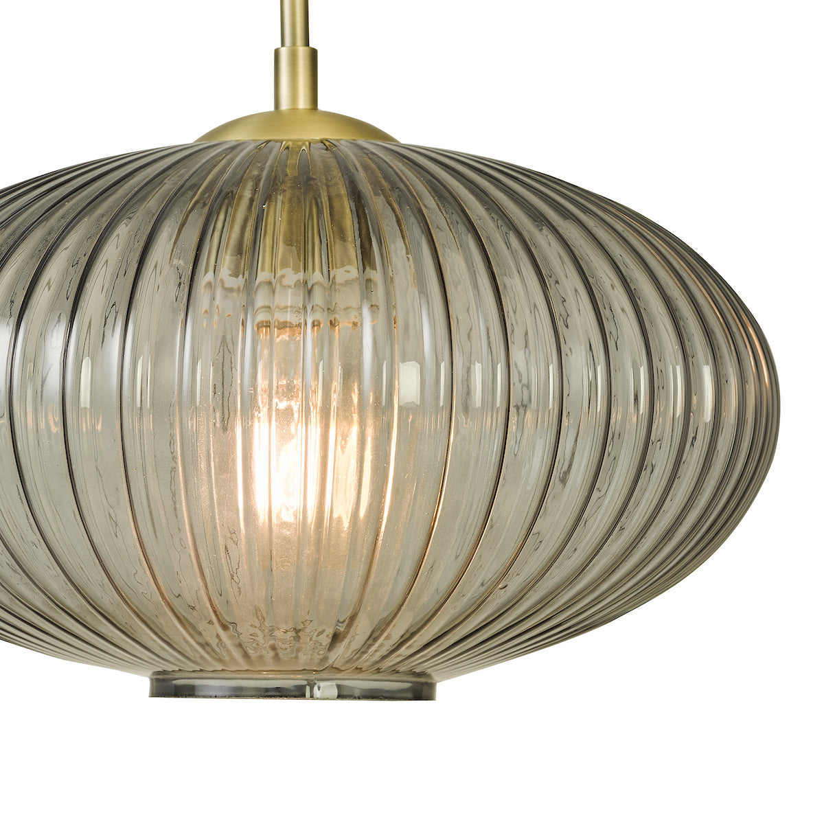 Close-up of a ribbed, smoked glass pendant light with a brass top and glowing bulb.