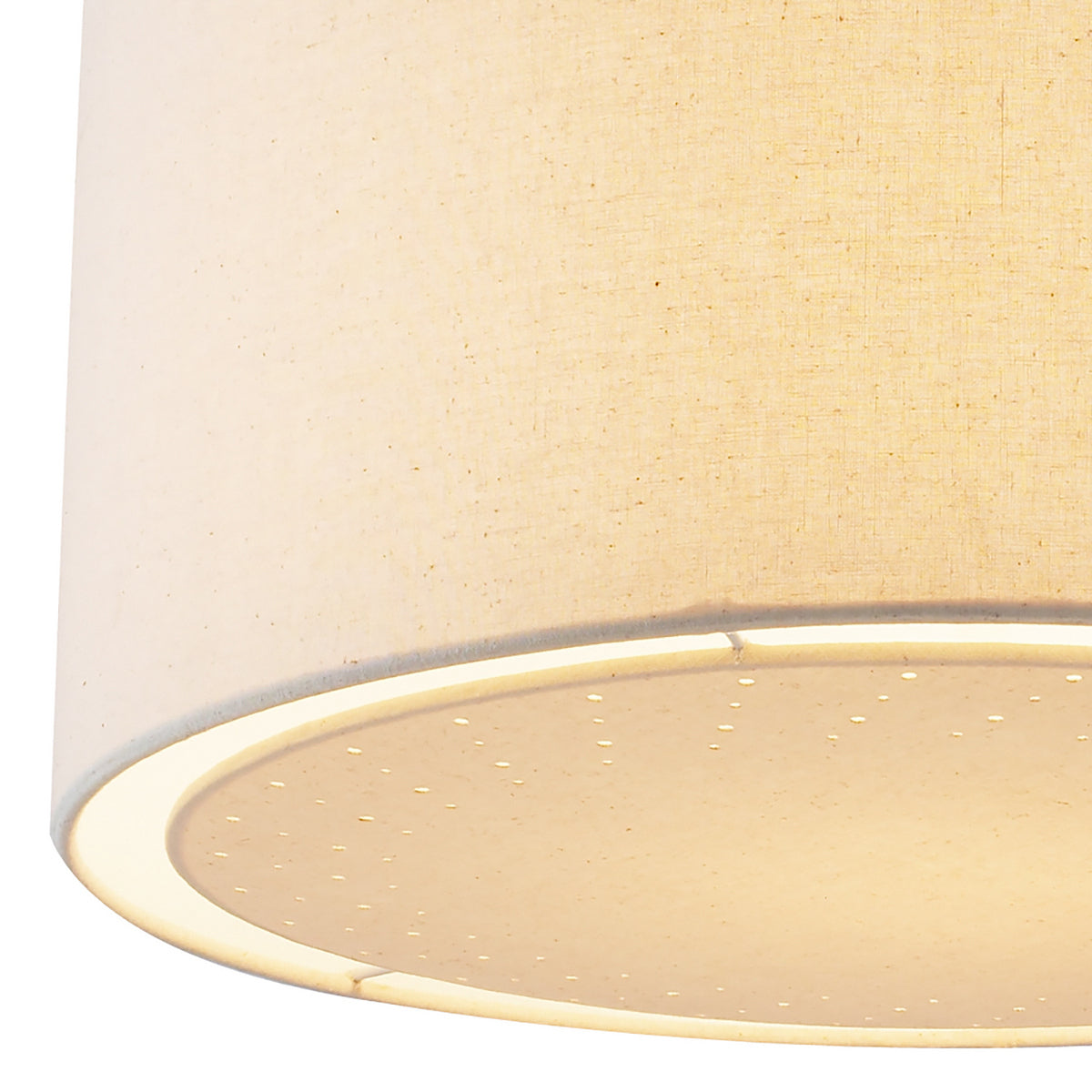 Close-up of a beige fabric lampshade with a perforated diffuser, illuminated from within.