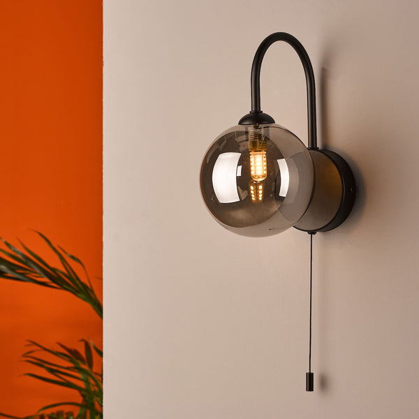 Black wall lamp with a smoked glass globe and a pull switch