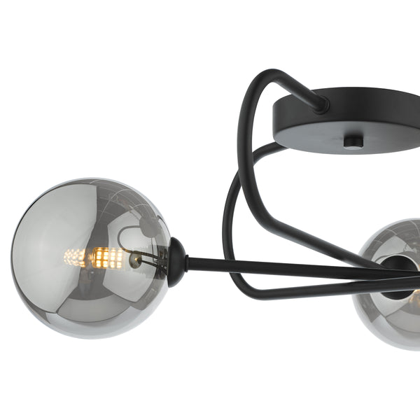 Close up of a black metal chandelier with three smoked glass globes, one with a lit LED bulb