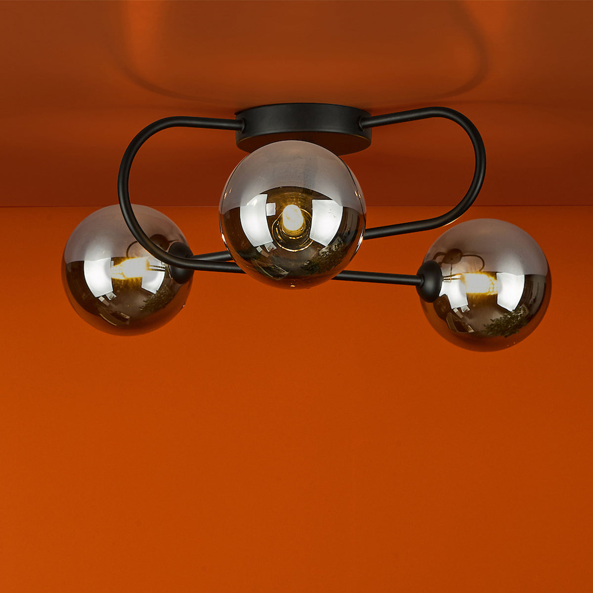 Three light ceiling fixture with smoked glass globes on a black metal frame