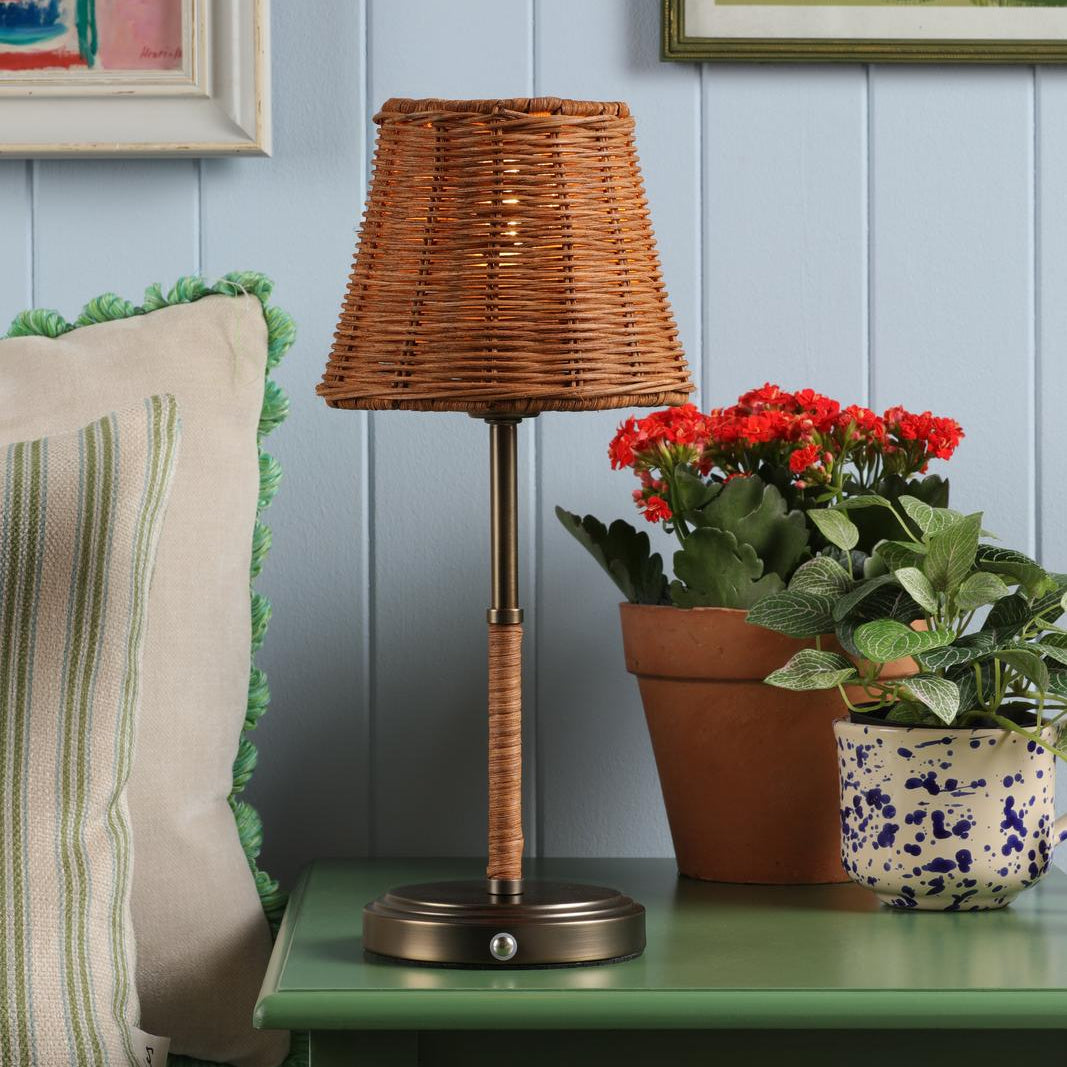 Table lamp with a woven rattan shade and a metal base on a green surface