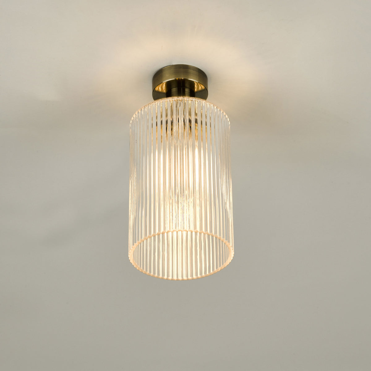 A brass ceiling light with a fluted glass shade illuminates a white ceiling.
